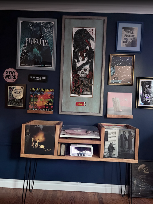 Wall with framed posters and records against a dark blue wall