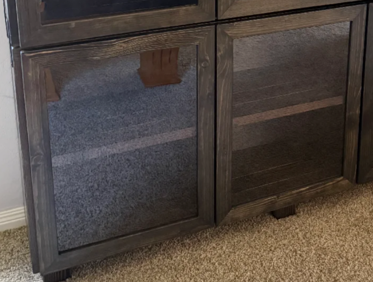 Dark wood cabinet with two glass doors and fabric-lined interior