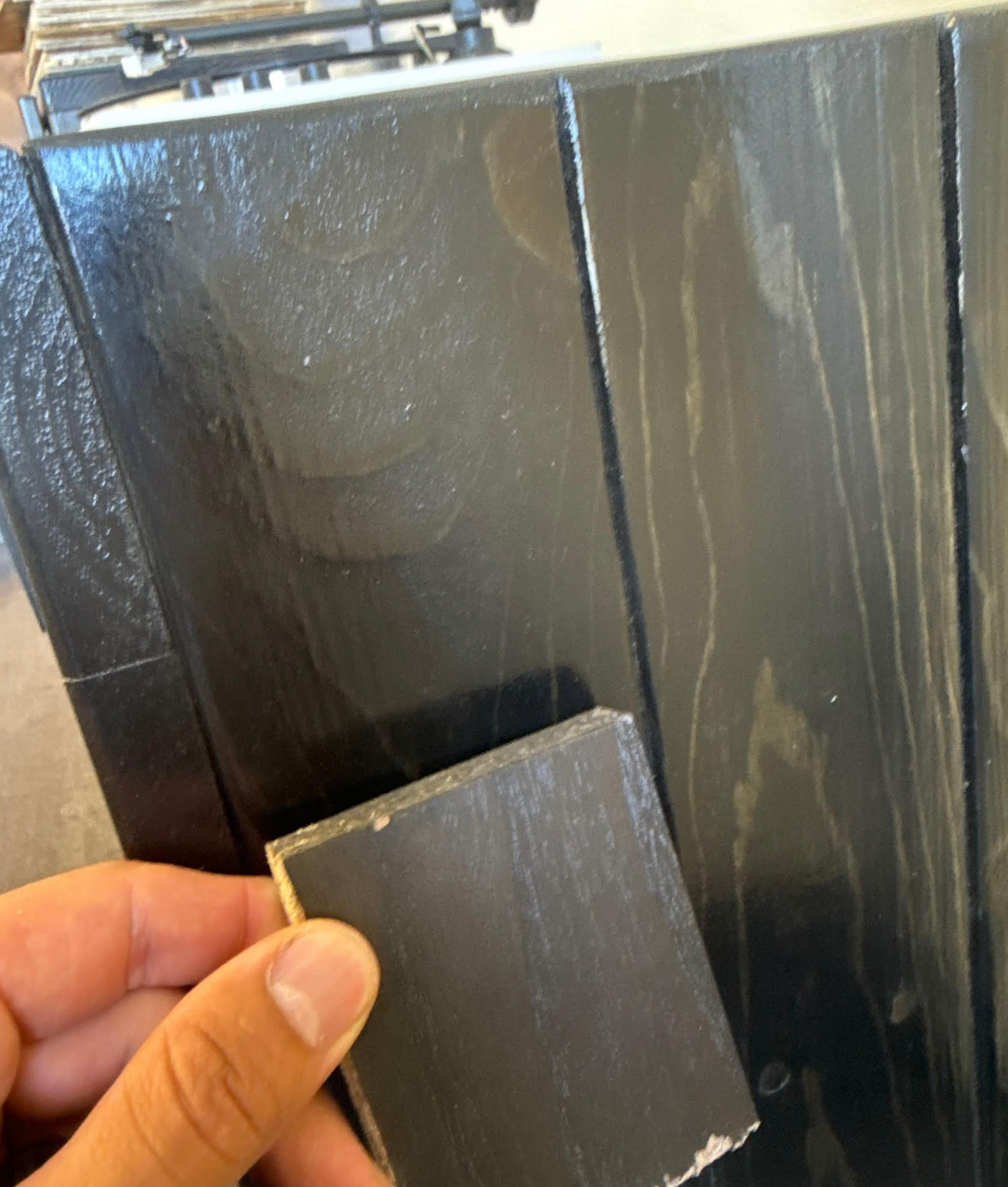 Dark gray/black rigid board sample with textured finish and squared edge